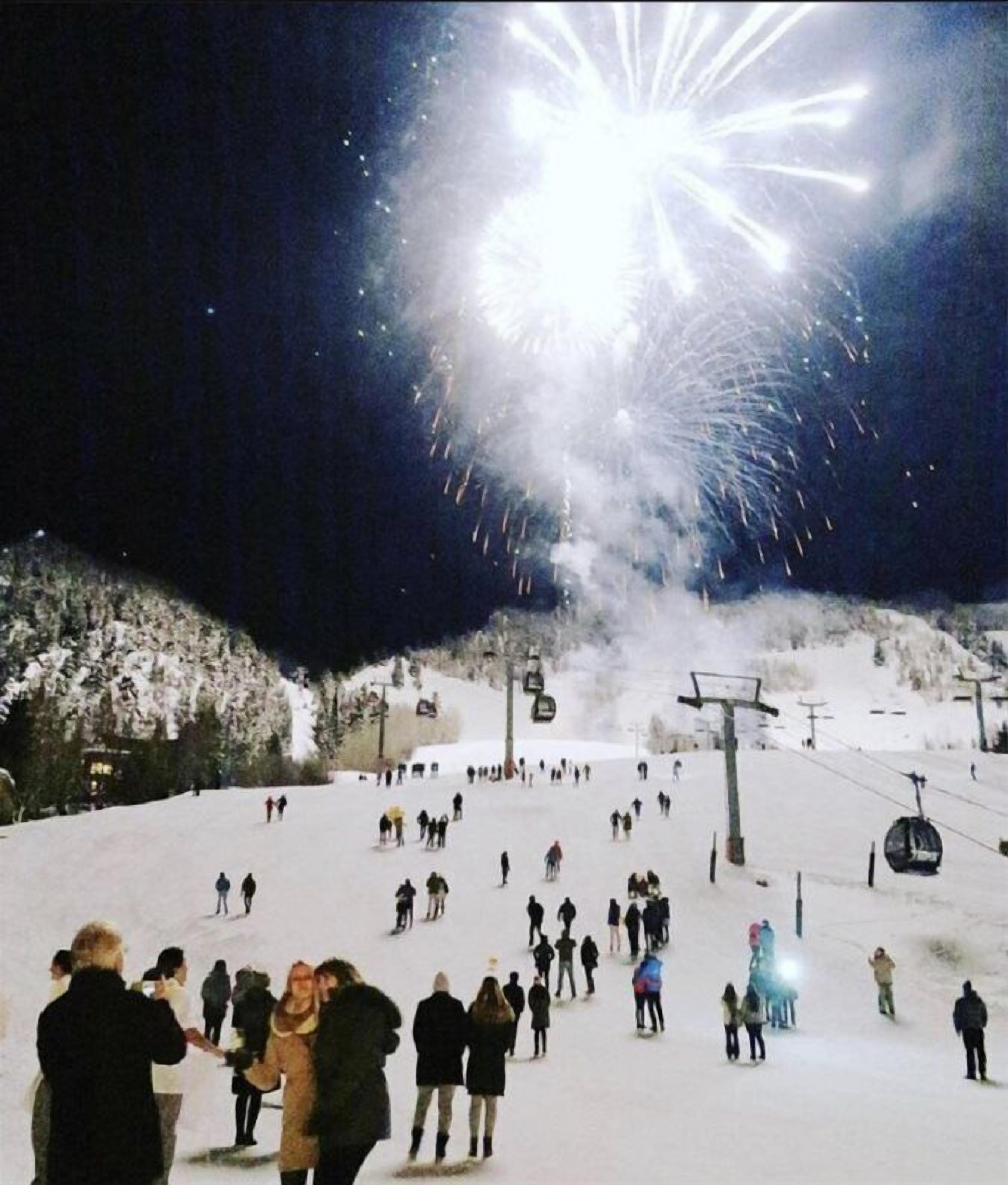 A ski slope with people skiing and standing, and a ski lift in the background.