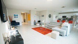 A modern living room with a grey sofa, red rug, and a black console table with candles. - Welcome to your Serene Retreat.  (Palm Bay)