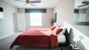 A bedroom with a bed, a ceiling fan, a window with blinds, and a nightstand with a vase of flowers. - Welcome to your Serene Retreat.  (Palm Bay)