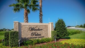 A sign for Windsor Palms, a gated resort community, with a stone wall and palm trees. - 4 Bed in Windsor Palms Resort - Steps to Disney (Kissimmee)