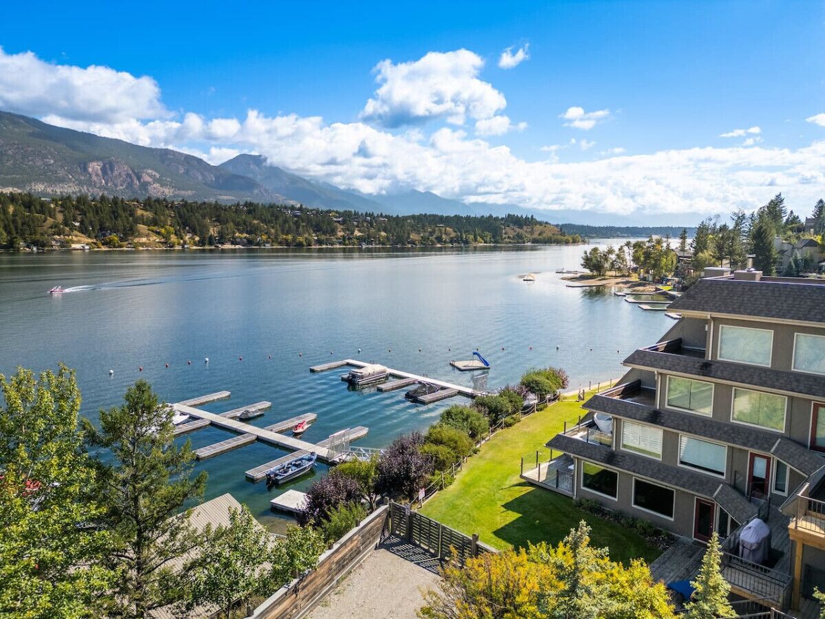 A lake with docked boats, a marina, and a multi-story building with balconies overlooking the water.