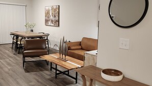 A modern living room with a dining area, a brown leather sofa, a wooden coffee table, and a round mirror on the wall. - Newly Built Getaway! (Columbia)
