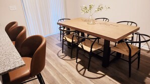 A dining area with a wooden table and six chairs, a vase with flowers, and a window with blinds. - Newly Built Getaway! (Columbia)