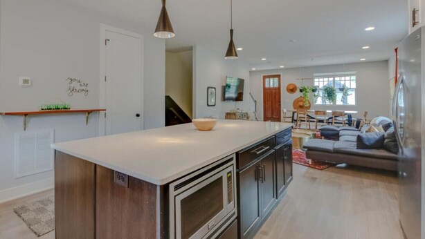 Een moderne keuken met een centraal eiland, een zithoek met een bank en stoelen, en een woonkamer met een televisie.
