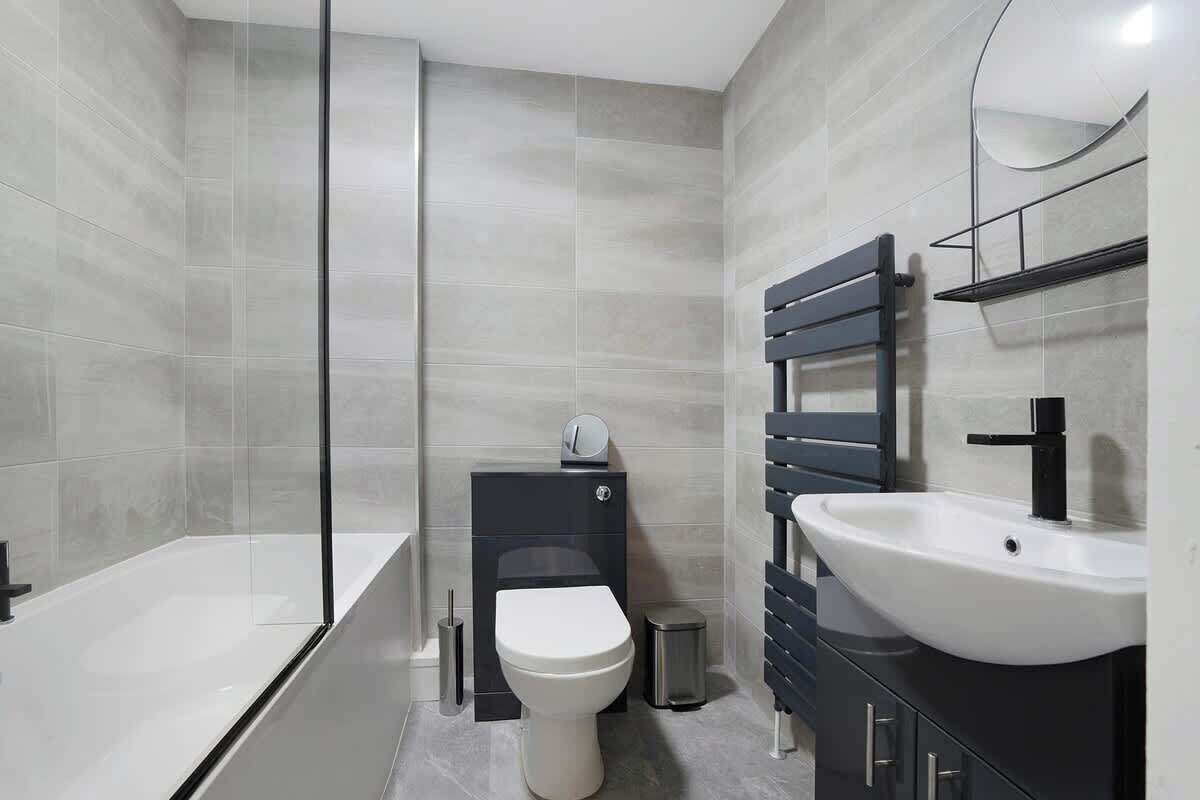 Ein modernes Badezimmer mit Badewanne, Toilette, Waschbecken und Spiegel.