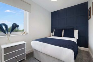 A bedroom with a bed, a dresser, a window with a view, and a dark headboard. - 3BR in County Durham with WiFi and Street Parking (Ludworth)