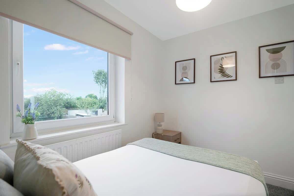 A bedroom with a bed, a bedside table, a lamp, and framed artwork on the wall.
