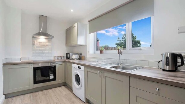 A modern kitchen with built-in appliances, a window with a view, and a clean, minimalist design. - 3BR in County Durham with WiFi and Street Parking (Ludworth)