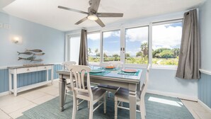 A dining area with a table, chairs, a ceiling fan, and a view through large windows. - Crystal Cove Beachfront Pool Tennis (St. Thomas)