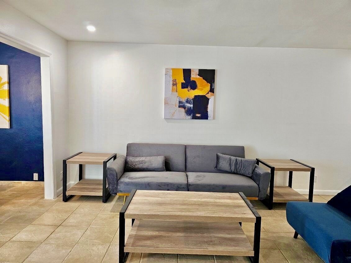 A living room with a grey sofa, two side tables, and a coffee table.