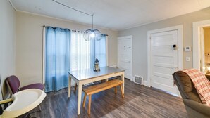 Un comedor con una mesa, banco, sillas y una lámpara colgante.