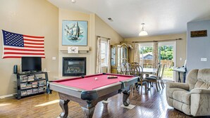 Un salon avec une table de billard, un téléviseur et une bibliothèque.