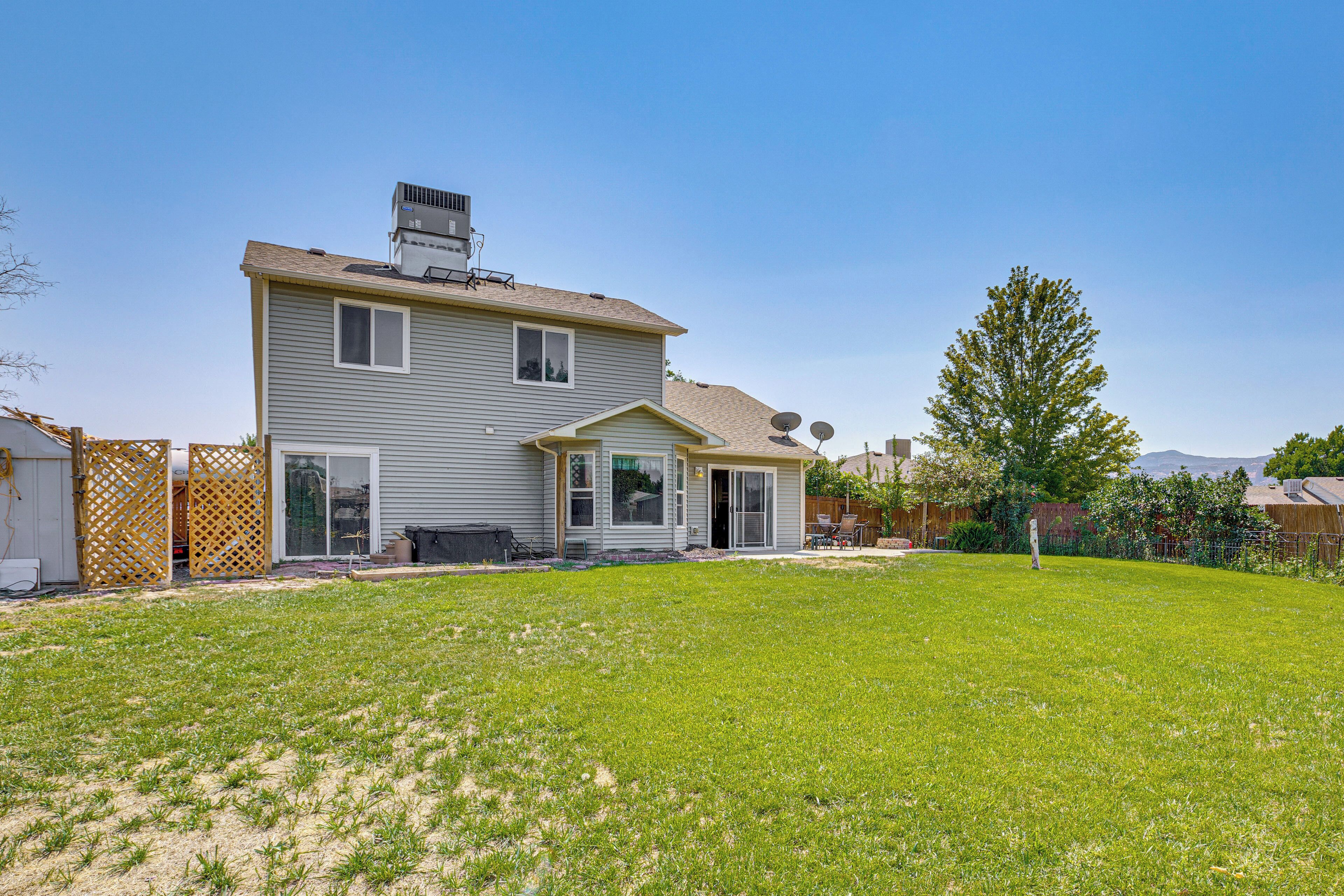 A two-story house with a large backyard, a covered patio, and a satellite dish.