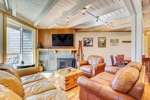 A cozy living room with a fireplace, leather sofas, and a wooden coffee table.