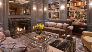A cozy living room with a fireplace, comfortable seating, and a bookshelf filled with books.