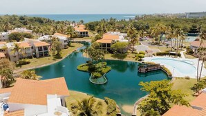 A resort with multiple buildings, a central swimming pool, and a view of the ocean. - Quaint villa Beach access Elina (Sabana)