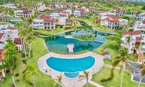 Een resort met meerdere gebouwen, een centraal gelegen zwembad en veel groen eromheen.