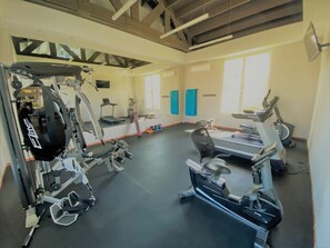 Une salle de sport équipée de divers appareils d’exercice, notamment des tapis de course et des appareils de musculation.