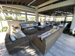 A covered outdoor seating area with wicker furniture and a glass-top coffee table. - Villa Quenepa with Generator & Steps from the Beach (Sabana)