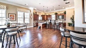 A spacious kitchen with wooden flooring, a central island, and modern bar stools.