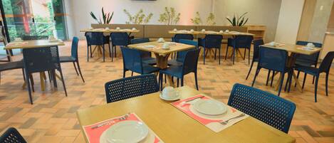 A restaurant with multiple tables and chairs, some with plates and cutlery set.