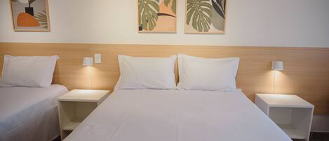 Habitación de hotel con dos camas individuales, cabecero de madera, lámparas de noche y decoración abstracta en la pared.
