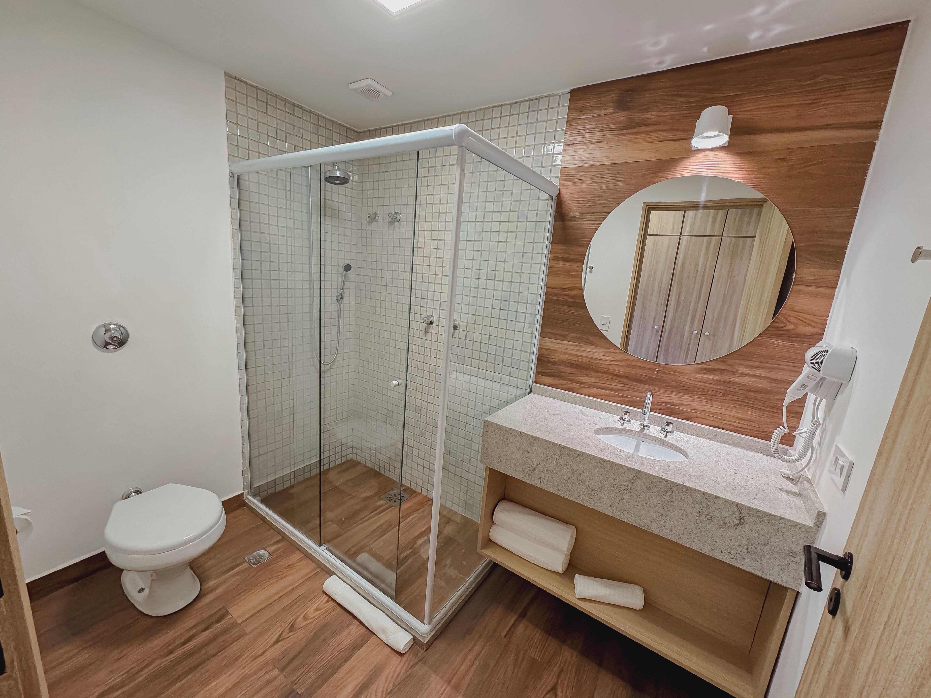Et moderne badeværelse med en brusekabine i glas, toilet og en vask med spejl.