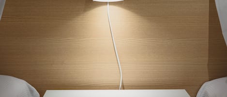 A hotel room with a wooden headboard, a bedside table, and a lamp.
