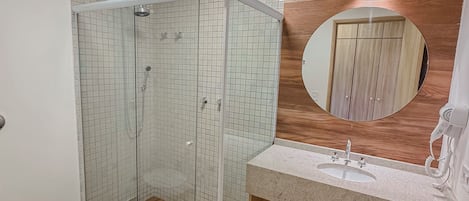 A modern bathroom with a glass-enclosed shower, a wooden vanity with a sink, and a toilet.