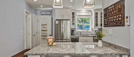 A modern kitchen with granite countertops, stainless steel appliances, and pendant lighting.