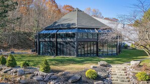 A modern glass conservatory with a metal frame, surrounded by a well-maintained lawn and a stone pathway. - Slopeside Escape by Avantstay Walk to Ski Lifts Arcade Games + Shuffleboard (Tannersville)