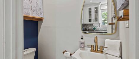 A bathroom with a white sink, gold faucet, and a mirror with a gold frame.