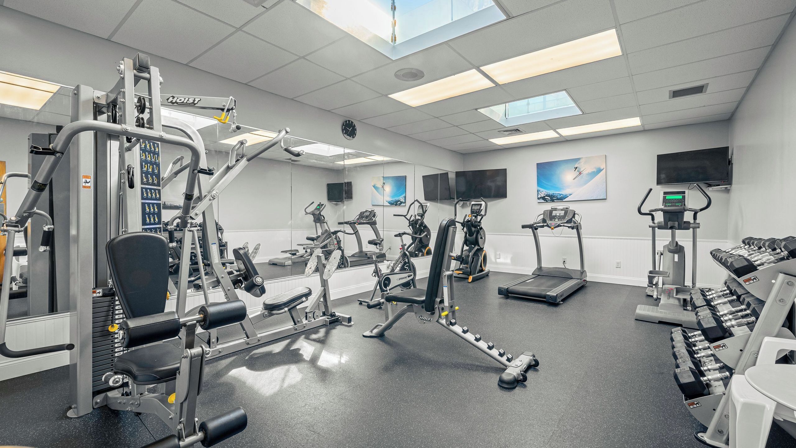 A gym with various exercise equipment, including treadmills, stationary bikes, and weight machines.