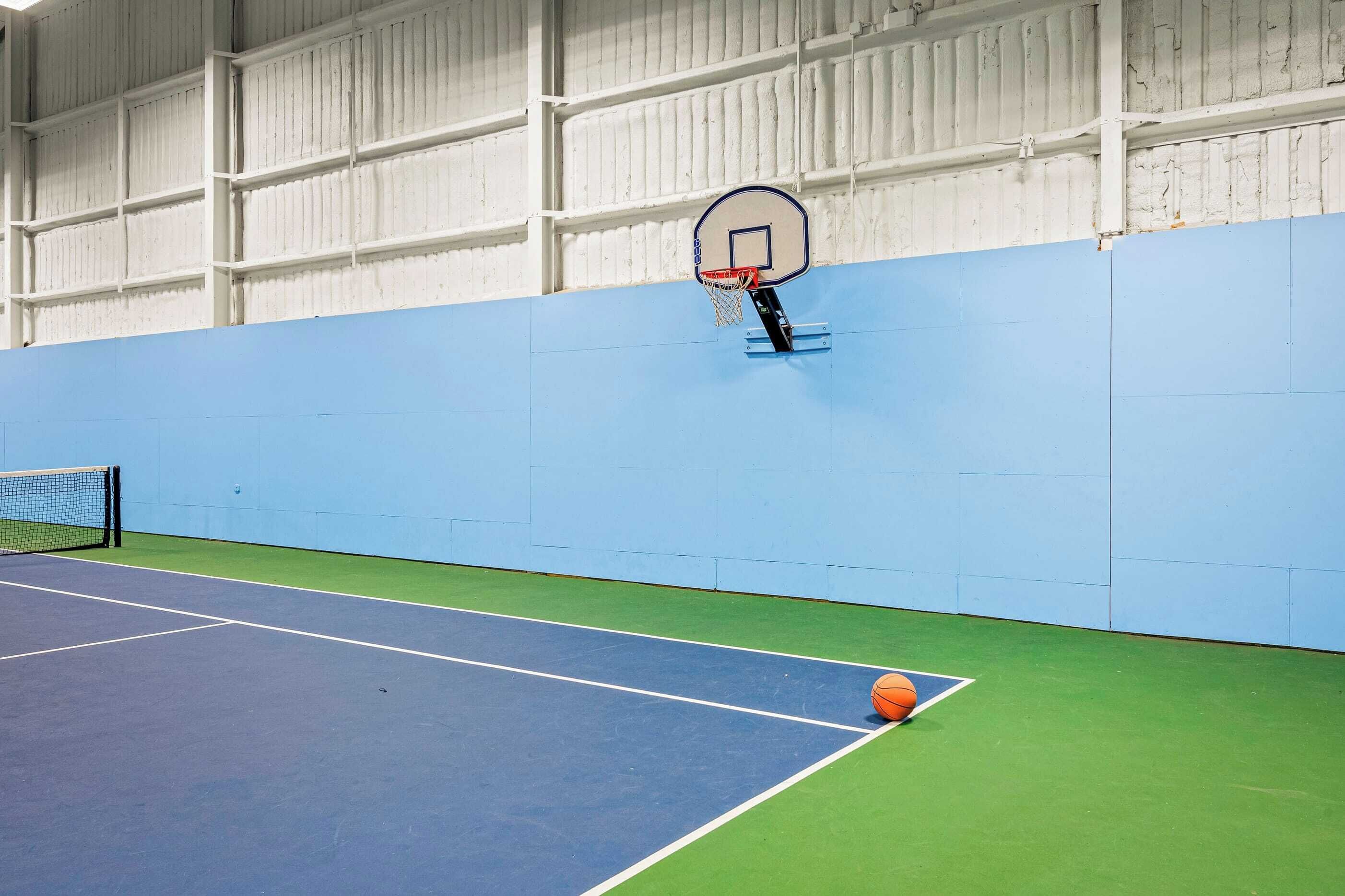 Eine Basketballhalle mit blauem Boden, einem grünen Bereich und einer weißen Wand mit einem Basketballkorb.