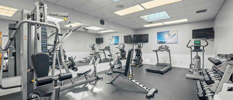 Ett gym med olika typer av träningsutrustning, inklusive löpband, styrketräningsmaskiner och fria vikter.