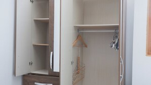 A walk-in closet with open doors, wooden drawers, and hanging space.