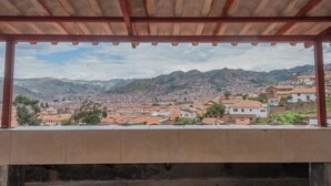 A view from a covered balcony overlooking a cityscape with mountains in the background.