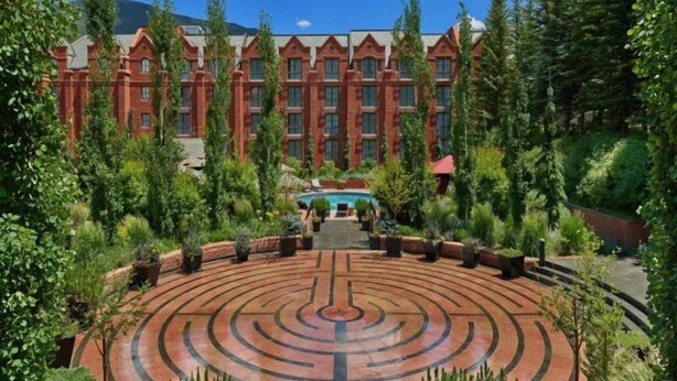 Un hotel grande con fachada simétrica, un patio central de diseño circular y abundante vegetación alrededor de la propiedad.