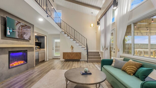 A spacious living area with a fireplace, a green sofa, a round coffee table, and a staircase leading to an upper level. - The Dock House (Savannah)