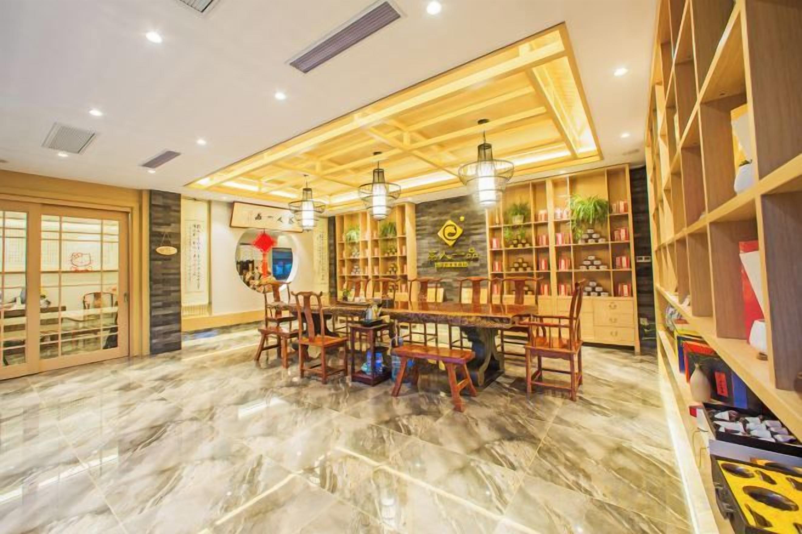 A hotel lobby with a marble floor, wooden furniture, and shelves with books and plants.