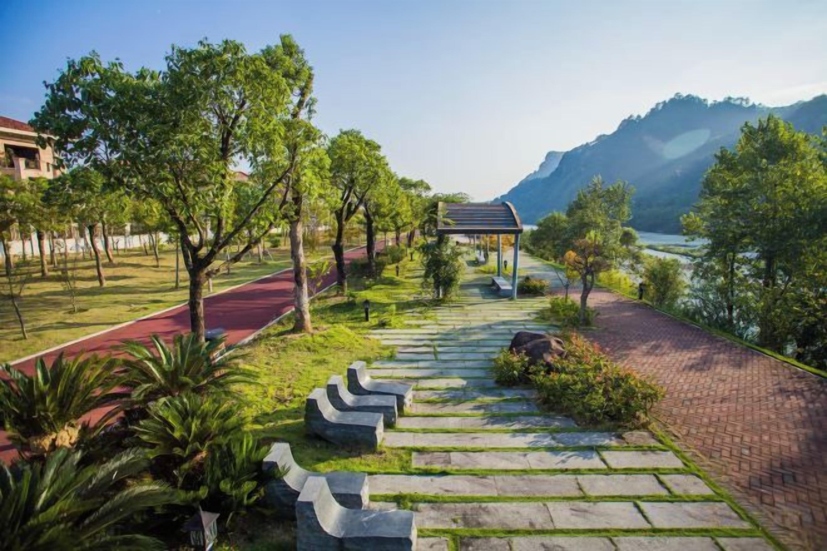 A pathway leading to a gazebo with a view of a lake and mountains.