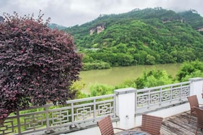 A balcony with a view of a river and hills. - Wuyishan Wuyi Yard Chinese Inn (Wuyishan)