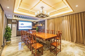 A conference room with a large wooden table, chairs, a projector screen, and a potted plant. - Wuyishan Wuyi Yard Chinese Inn (Wuyishan)