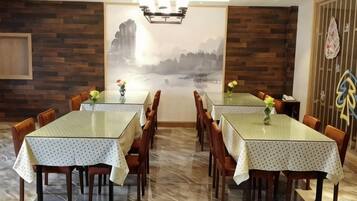 Un comedor con dos mesas, sillas de madera y un mural en la pared.