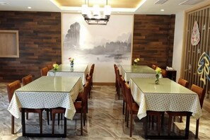 Un comedor con dos mesas, sillas de madera y un mural en la pared.
