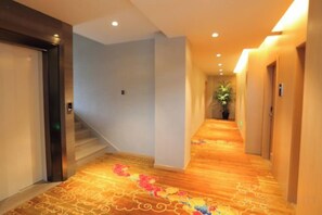 Un pasillo de hotel con piso alfombrado, una escalera y puertas que dan a habitaciones.