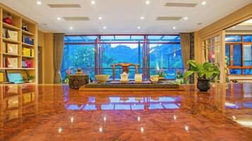 Un vestíbulo espacioso con piso de mármol pulido, una recepción y ventanas amplias con vistas al exterior.