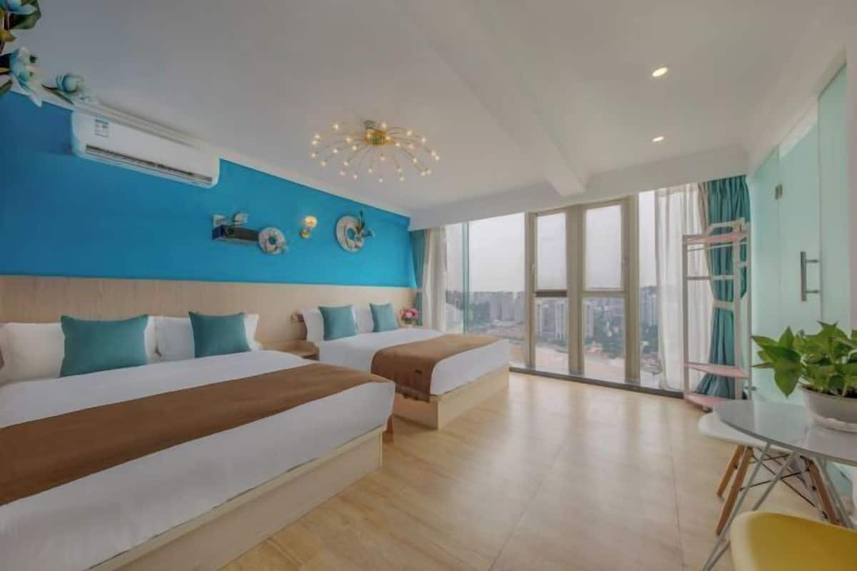Ein modernes Hotelzimmer mit zwei Betten, einem großen Fenster mit Blick auf die Stadt und einem Essbereich mit Tisch und Stühlen.