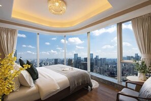 A bedroom with a large bed, a view of the city, and a chandelier.