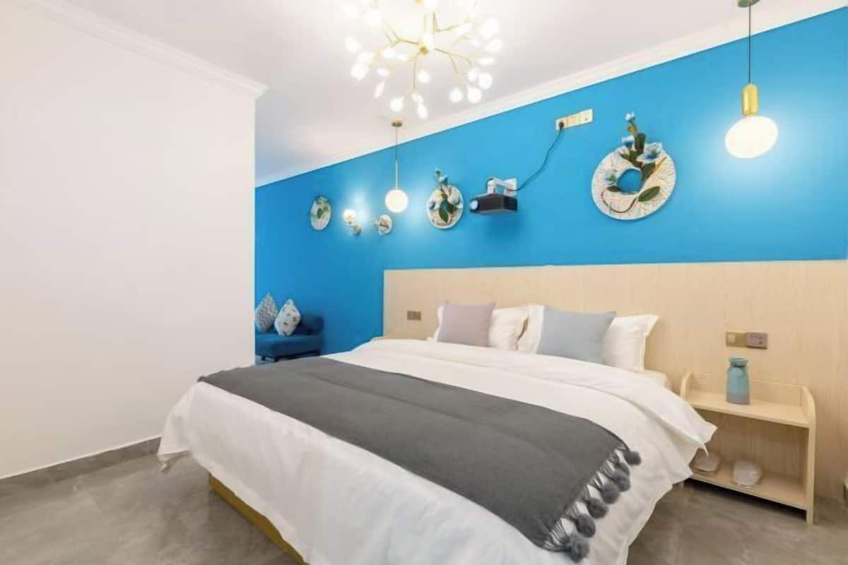 Ein modernes Schlafzimmer mit einem großen Bett, einer blauen Akzentwand und Wanddekoration.